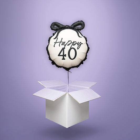 Czarno-biały balon foliowy w kształcie medalionu z kokardą i napisem „Happy 40”, wypełniony helem i wyskakujący z białego kartonu – stylowy prezent na 40. urodziny.