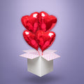 Cztery czerwone balony foliowe w kształcie serc, wypełnione helem i wyskakujące z białego kartonu z różową kropkowaną wyściółką – romantyczna niespodzianka na Walentynki, rocznicę lub urodziny ukochanej osoby.